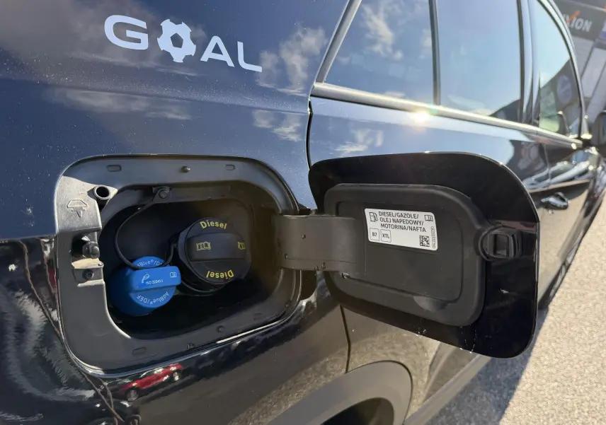 Vue rapprochée de la trappe à carburant ouverte côté gauche d’un Volkswagen T-Roc noir avec bouchon diesel visible.