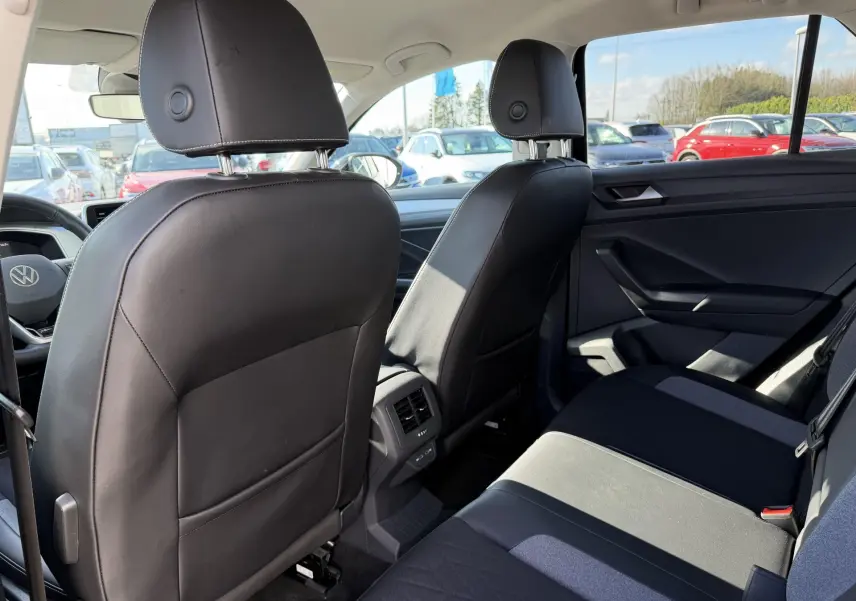 Vue intérieure arrière côté droit du Volkswagen T-Roc 2025 noir, montrant les sièges avant en cuir et la banquette arrière tissu.