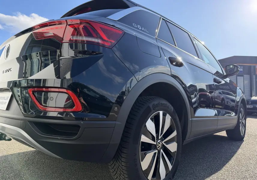 Vue 3/4 arrière droite d'un Volkswagen T-Roc noir avec jantes alliage 17 pouces et feux arrière LED distinctifs.