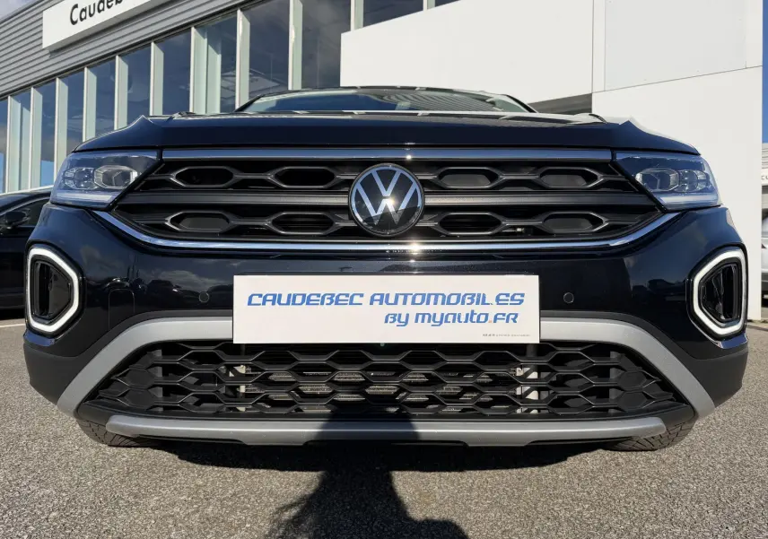 Vue frontale rapprochée du Volkswagen T-Roc noir avec calandre hexagonale et feux LED intégrés.