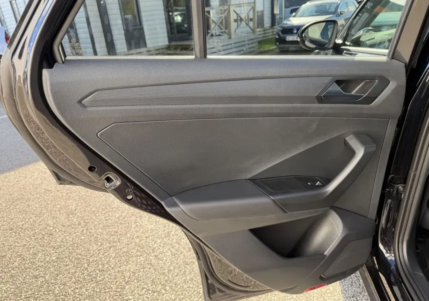 Vue intérieure de la porte arrière droite noire du Volkswagen T-Roc 2025, avec poignée et commande de vitre visible.
