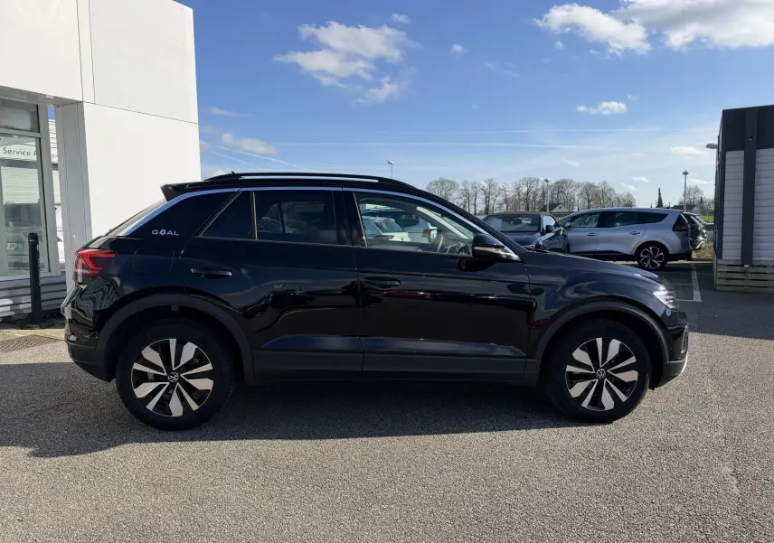 Vue de profil côté gauche d'un Volkswagen T-Roc noir 2025 avec jantes alliage 17 pouces et vitres surteintées.