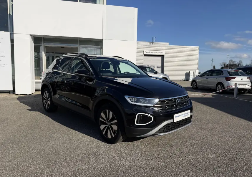 Volkswagen T-Roc noir vue 3/4 avant droit, avec jantes alliage et calandre distinctive, stationné devant un bâtiment.
