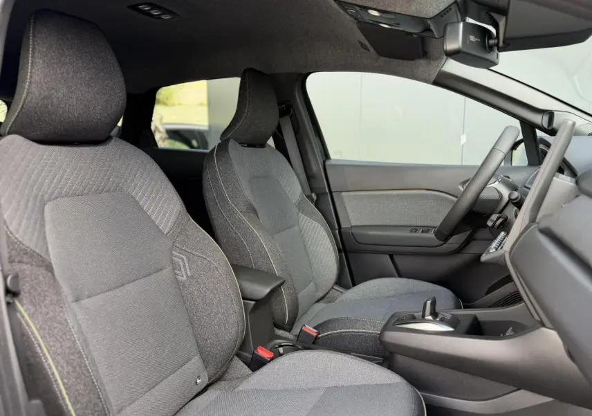 Vue intérieure côté droit du Renault Captur 2026, sièges gris tissu avec surpiqûres jaunes et console centrale noire.