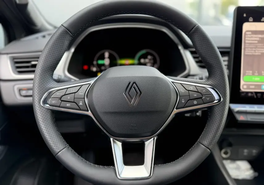 Vue rapprochée du volant noir perforé du Renault Captur 2026 avec commandes intégrées et logo central chromé.