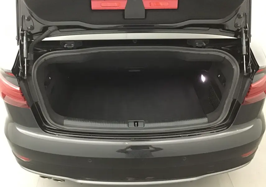 Coffre ouvert vu de l'arrière d'une Audi A3 Cabriolet noir 2020, montrant l'espace de chargement vide et éclairé.