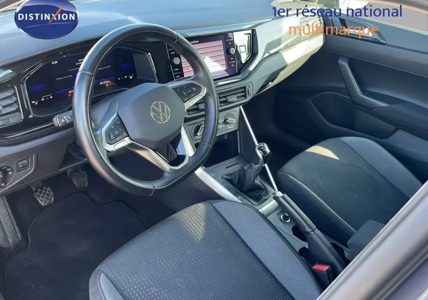 Vue intérieure du Volkswagen Taigo 1.0 TSI 110CH LIFE 2022, volant multifonction, tableau de bord numérique et sièges tissu gris.