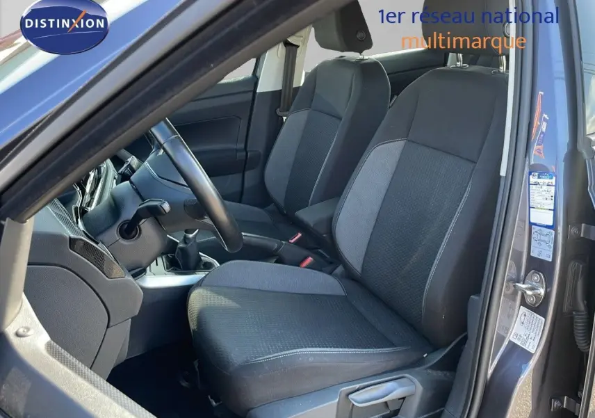 Vue intérieure côté conducteur du Volkswagen Taigo gris cendre 2022, sièges tissu gris et noir, boîte manuelle visible.