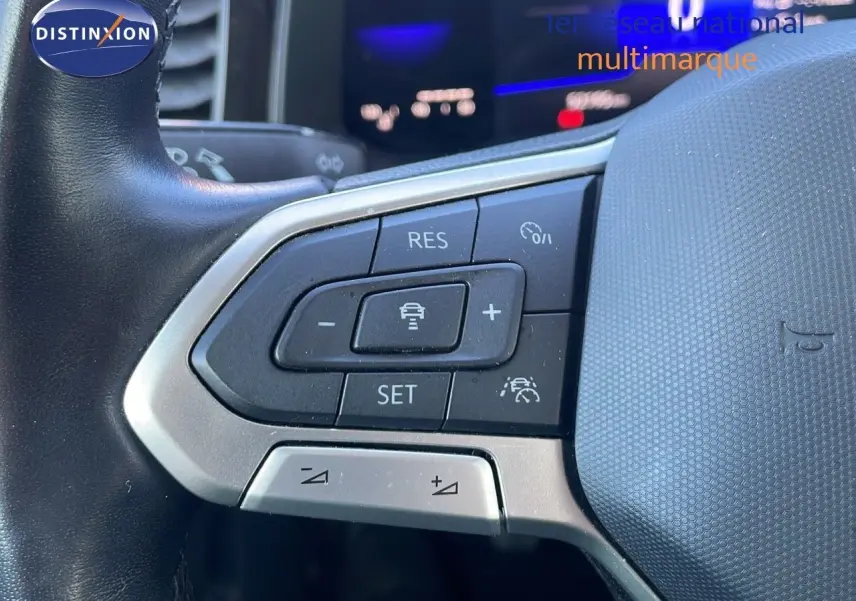 Gros plan sur les commandes au volant du Volkswagen Taigo gris cendre 2022, mettant en valeur les boutons de régulateur de vitesse.