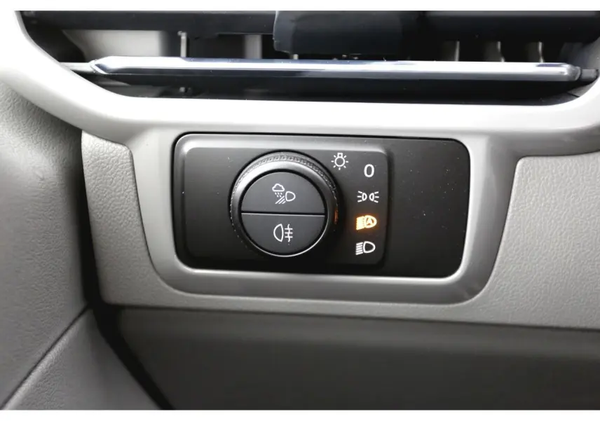 Gros plan sur la molette de commande des phares du Volkswagen Transporter T7 Business, intérieur gris clair.