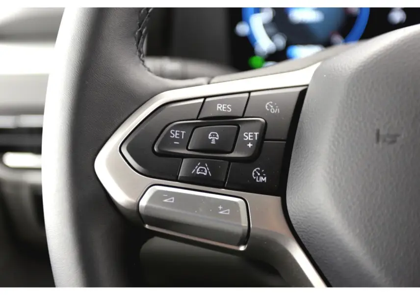 Gros plan sur les commandes multifonctions du volant du Volkswagen Transporter T7 Business gris Stone, 2025.