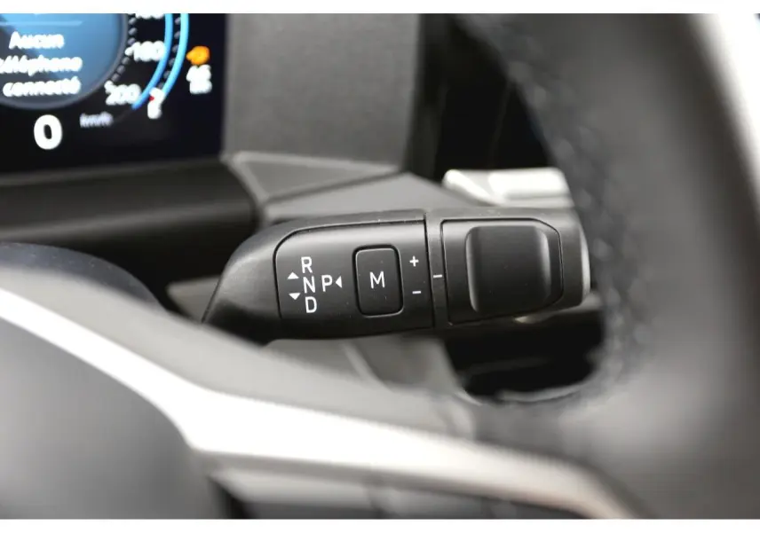 Gros plan sur la commande de boîte automatique du Volkswagen Transporter T7, intérieur noir avec écran digital partiel visible.