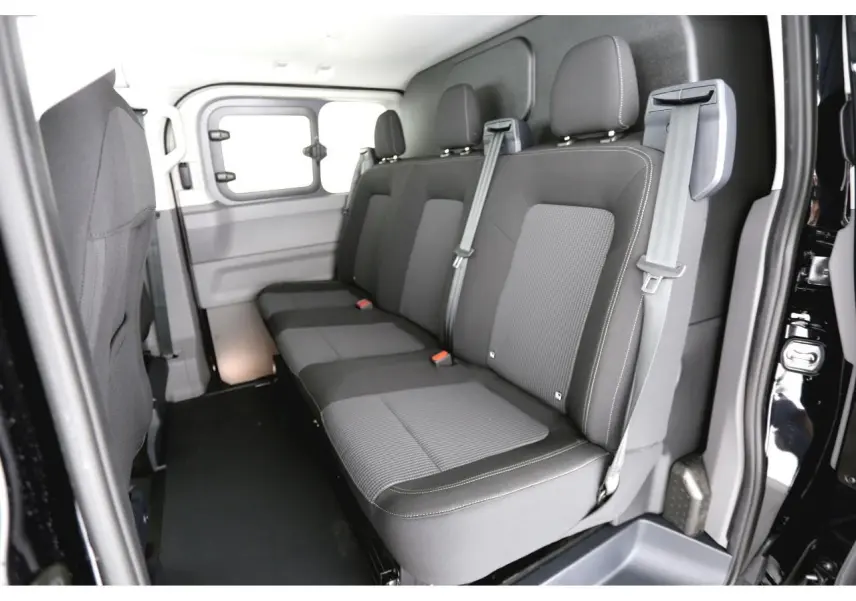 Vue intérieure côté droit montrant la banquette arrière grise du Volkswagen Transporter T7 ProCab 2025 avec ceintures de sécurité.