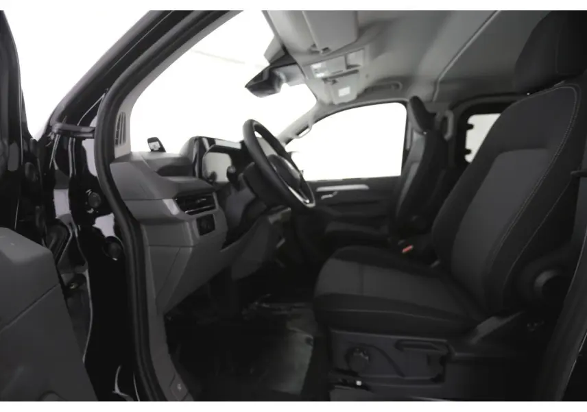 Vue intérieure côté gauche du Volkswagen Transporter T7 2025, montrant sièges noirs et tableau de bord moderne.