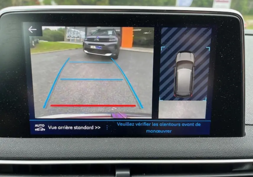 Écran de caméra de recul montrant l'arrière d'un Peugeot 3008 rouge Ultimate avec lignes de guidage bleues et rouges.