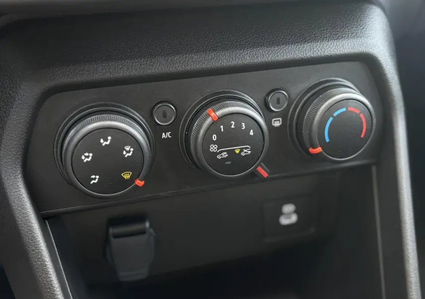 Gros plan sur les commandes de climatisation manuelle noires du tableau de bord de la Dacia Sandero Stepway 2025.