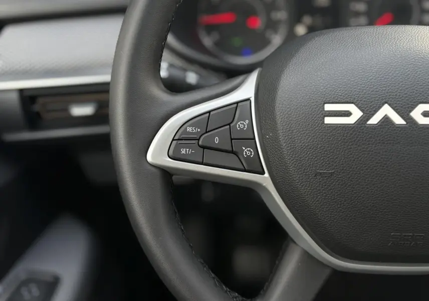 Gros plan sur le volant noir de la Dacia Sandero Stepway 2025, mettant en valeur les commandes de régulateur de vitesse à gauche.