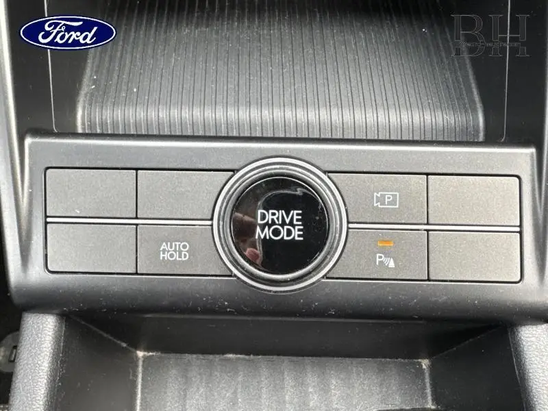 Gros plan sur la console centrale noire avec bouton rotatif Drive Mode et commandes de stationnement du Hyundai Kona Denim Blue 2023