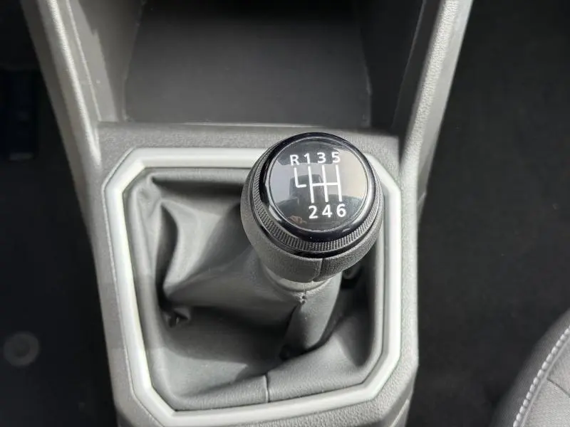 Gros plan sur le levier de vitesses manuel du Dacia Jogger 2025, entouré d’une garniture grise, intérieur sobre.