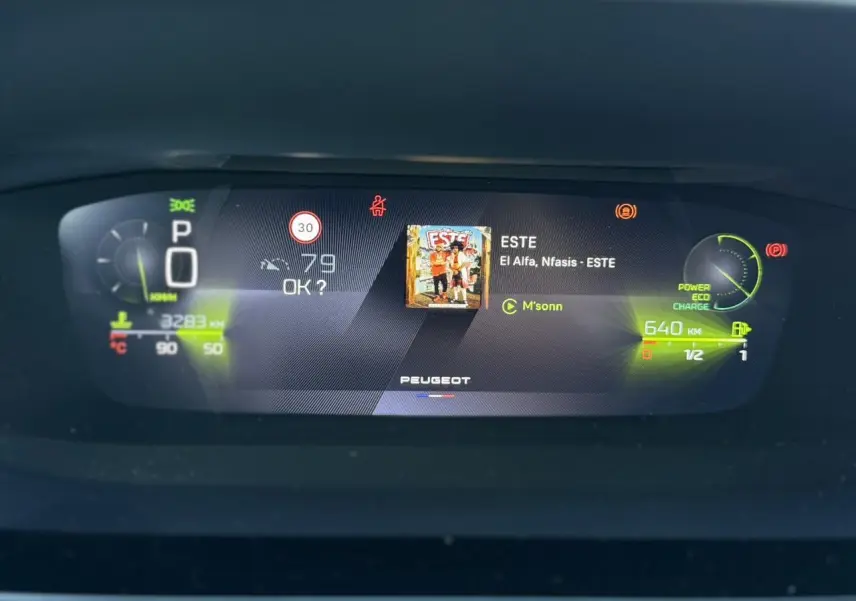 Affichage numérique du combiné Peugeot 408 Hybrid 2025 avec informations de conduite et musique en cours.
