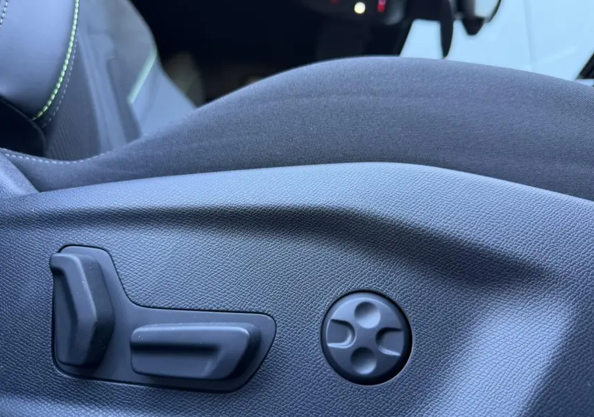 Gros plan sur les commandes électriques de réglage du siège conducteur en alcantara noir du Peugeot 408 Hybrid blanc.