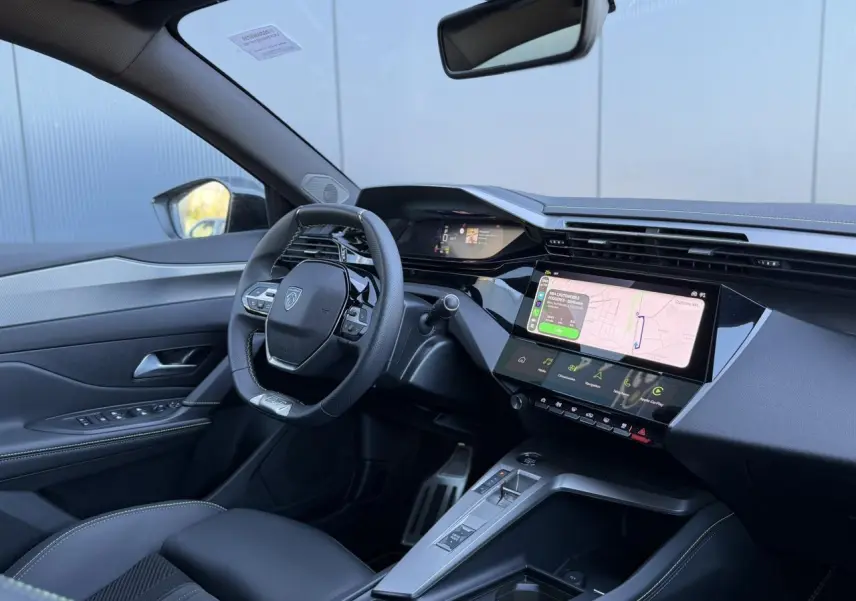 Vue intérieure côté conducteur du Peugeot 408 Hybrid 145 GT 2025, avec tableau de bord numérique et écran tactile central.