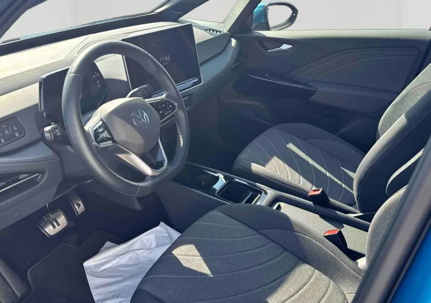 Vue intérieure côté conducteur du Volkswagen ID.3 bleu 2025, avec volant multifonction et sièges tissu gris.