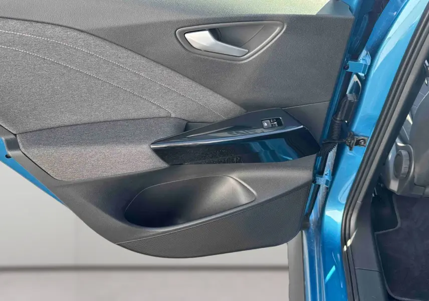 Vue rapprochée de la porte avant gauche bleu métallisé du Volkswagen ID.3 avec garniture noire et commandes de fenêtre.
