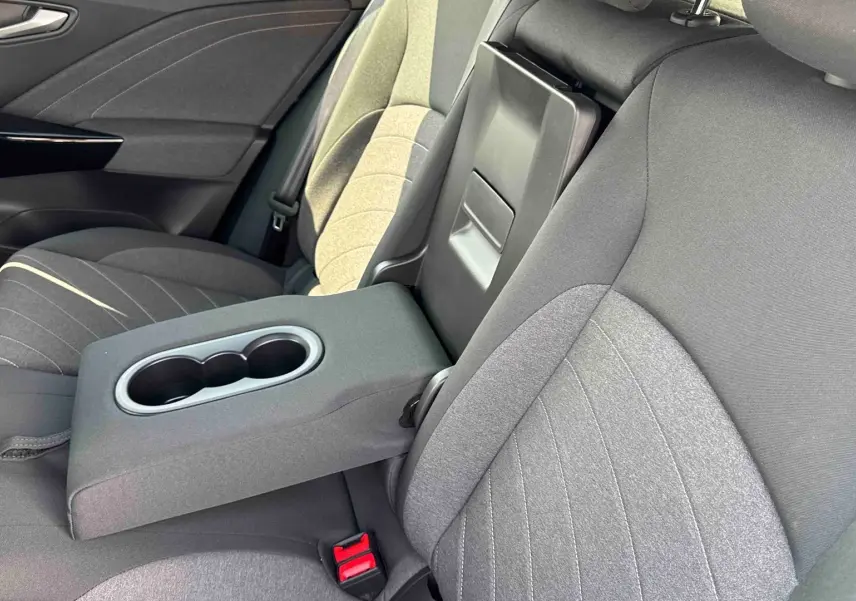 Vue intérieure côté droit des sièges arrière gris avec accoudoir central relevé et porte-gobelets du Volkswagen ID.3 2025.