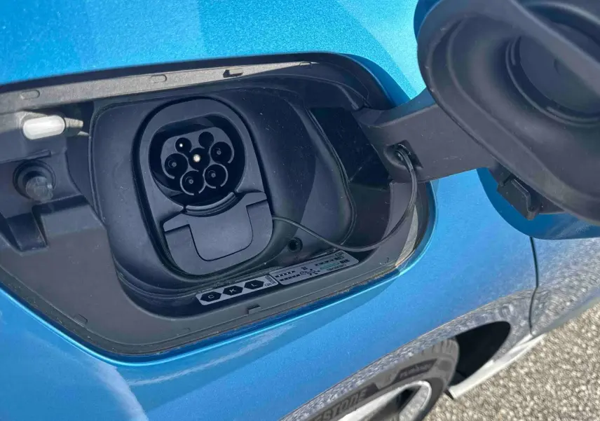 Prise de recharge électrique ouverte sur le côté gauche d'une Volkswagen ID.3 bleue métallisée.