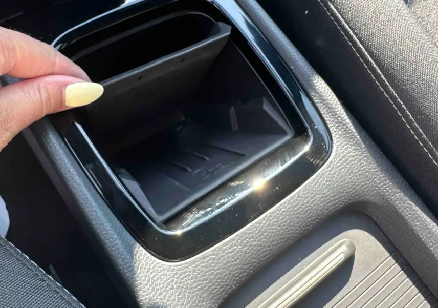 Détail de la console centrale noire avec rangement ouvert et siège tissu gris dans une Volkswagen ID.3 2025.