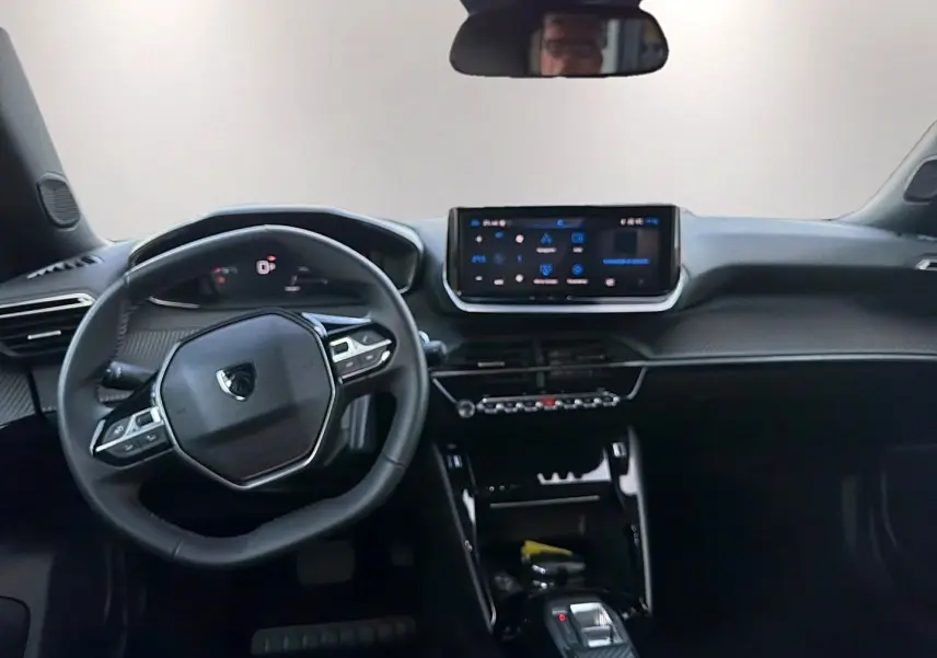Vue intérieure avant du Peugeot 2008 1.2 hybrid 145 allure e-dcs6, tableau de bord et volant multifonction noirs.