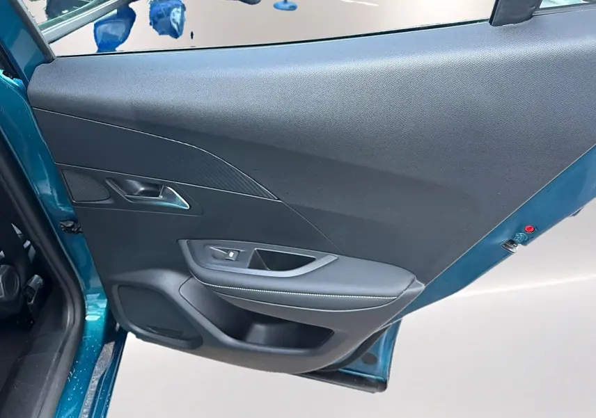 Vue rapprochée de la porte arrière gauche bleu obsession du Peugeot 2008 1.2 hybrid 145 allure e-dcs6 avec garniture noire.
