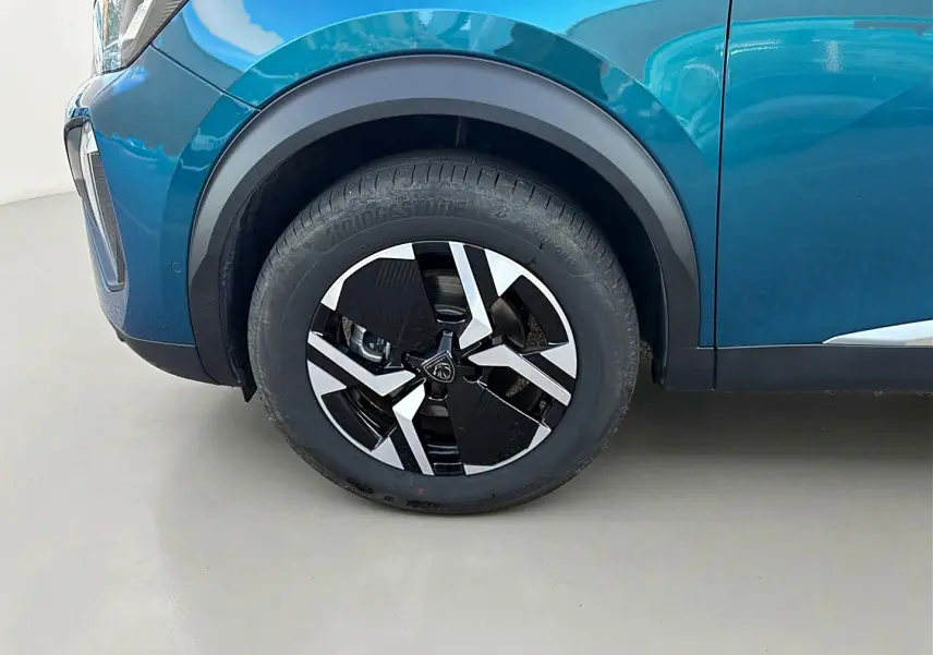 Gros plan sur la roue avant gauche d’un Peugeot 2008 bleu obsession avec jante alu au design moderne.