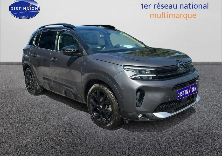 Vue 3/4 avant gauche du Citroën C5 Aircross gris platinium avec jantes noires et barres de toit visibles.