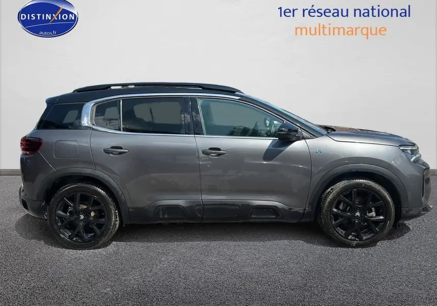 Profil côté gauche du Citroën C5 Aircross gris platinium avec jantes noires et barres de toit visibles.