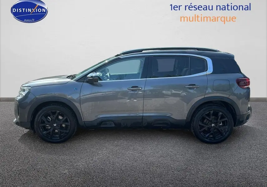 Profil droit du Citroën C5 Aircross gris platinium 2024 avec jantes noires et barres de toit visibles.