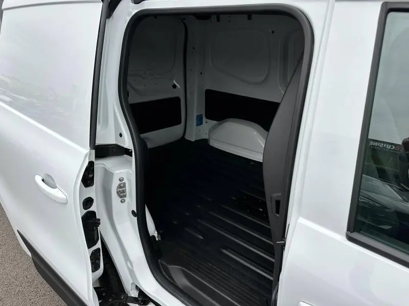 Vue rapprochée de la porte latérale droite ouverte du Nissan Townstar blanc minéral, montrant l'espace de chargement vide.