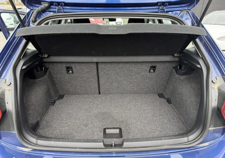 Coffre ouvert d'une Volkswagen Polo bleu 3/4 arrière, montrant un espace de chargement propre et spacieux.