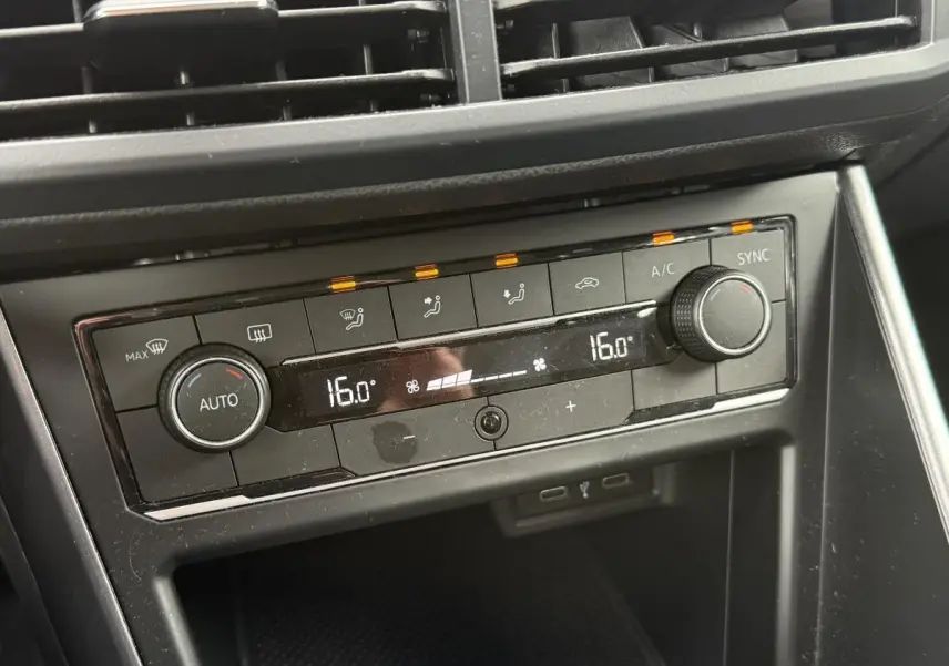Gros plan sur la console centrale noire de la Volkswagen Polo 1.0 TSI R-Line 2021, affichant la climatisation automatique à 16°C.