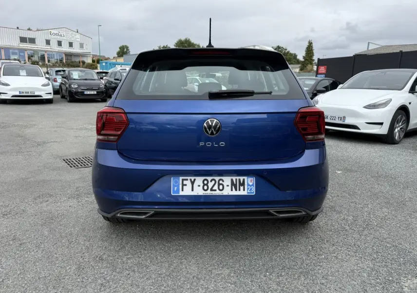 Vue arrière d'une Volkswagen Polo bleu métallisé avec logo et feux arrière foncés, immatriculée en France.