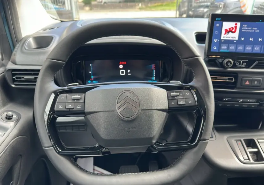 Vue intérieure centrée sur le volant du Citroën Berlingo 2025 Kiama blue, avec tableau de bord numérique et écran tactile.