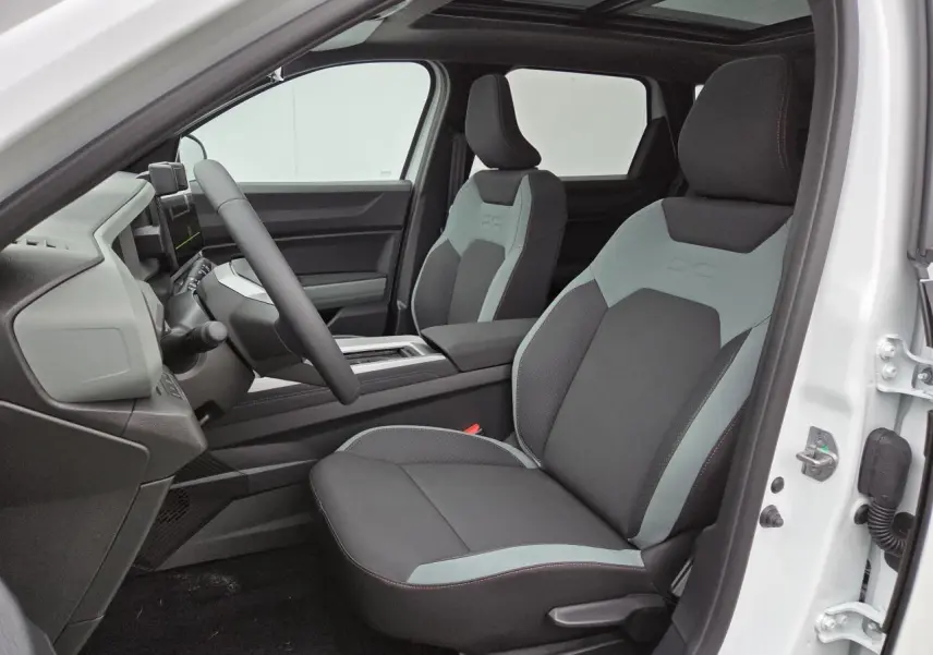 Vue intérieure côté conducteur du Dacia Bigster blanc glacier 2025 avec sièges bicolores et toit panoramique ouvrant.