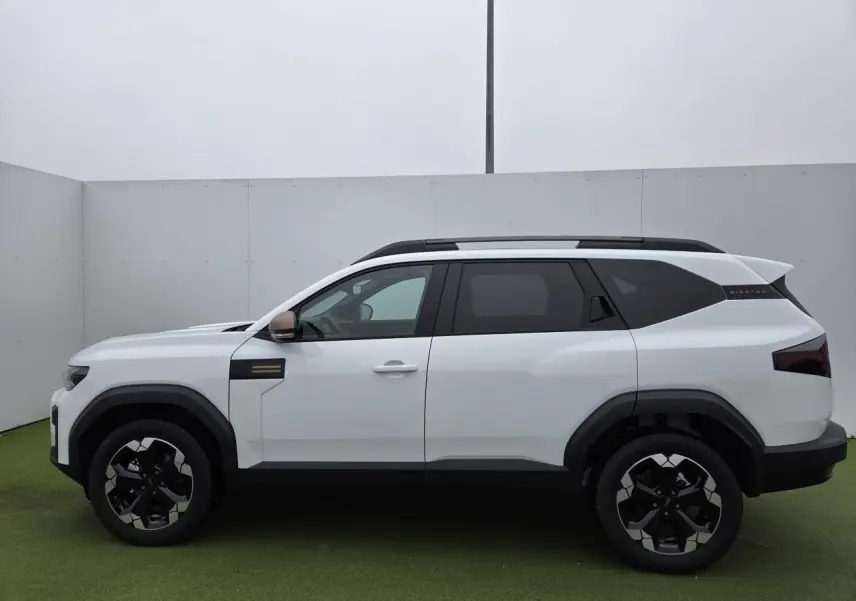 Profil côté gauche du Dacia Bigster blanc glacier 2025 avec jantes 18'' semi-diamantées et rétroviseurs brun cuivré.