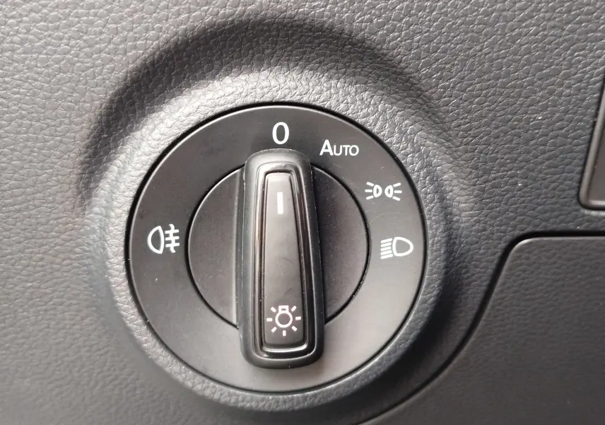 Gros plan sur la molette de réglage des phares du tableau de bord du SEAT Arona blanc, avec options d’éclairage visibles.