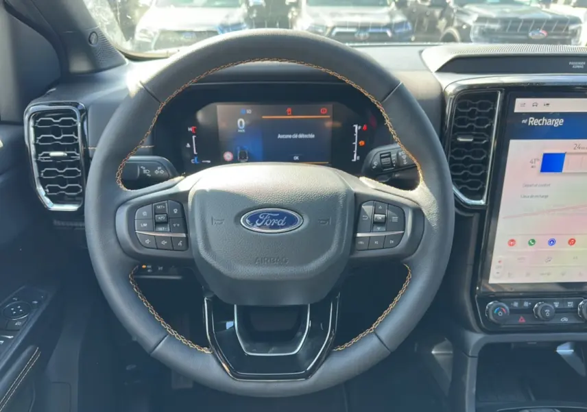 Vue intérieure centrée sur le volant cuir noir avec surpiqûres marron et écran tactile du Ford Ranger blanc 2026.