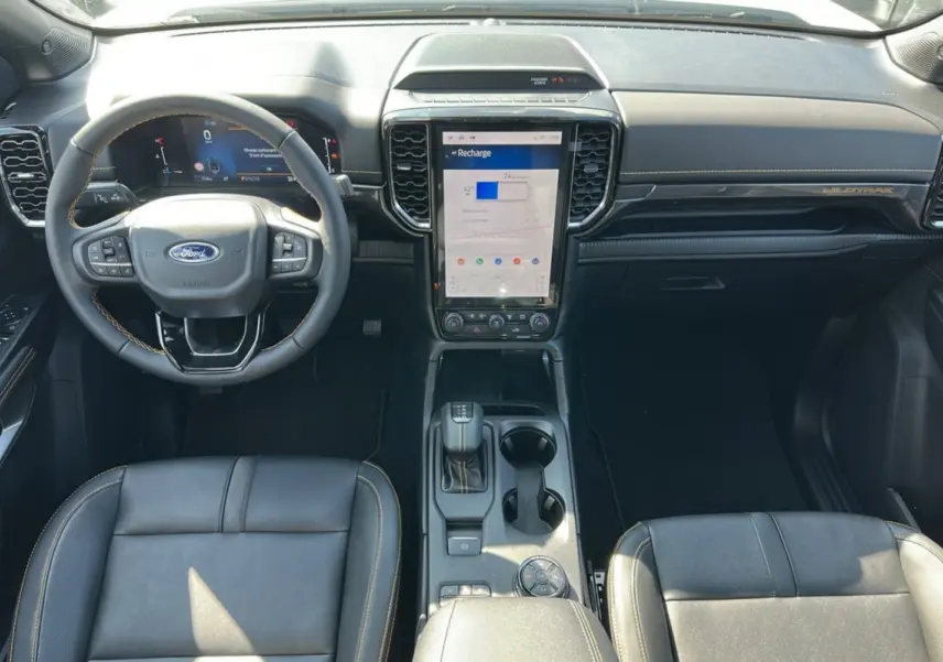 Vue intérieure avant du Ford Ranger Wildtrak blanc 2026, avec volant cuir multifonctions et écran tactile vertical central.