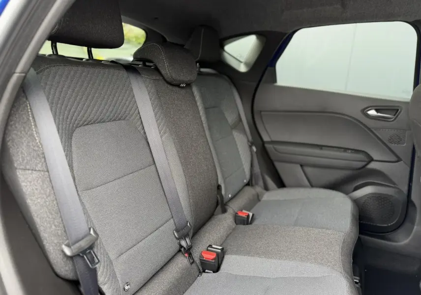 Vue intérieure arrière côté droit des sièges gris foncé du Renault Captur 2026 avec ceinture et porte de teinte sombre.
