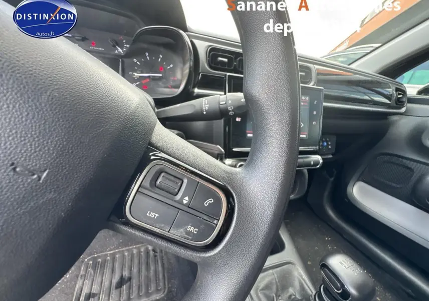 Gros plan sur le volant multifonction noir et la console centrale d'une Citroën C3 2023 diesel avec boîte manuelle.