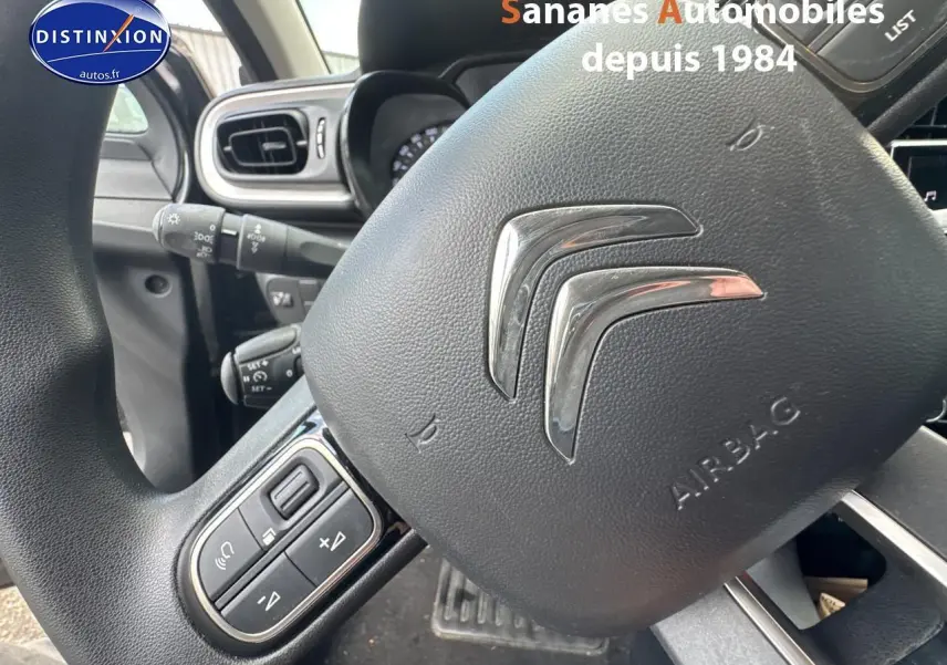 Gros plan sur le volant noir de la Citroën C3 2023 avec commandes audio intégrées côté gauche.